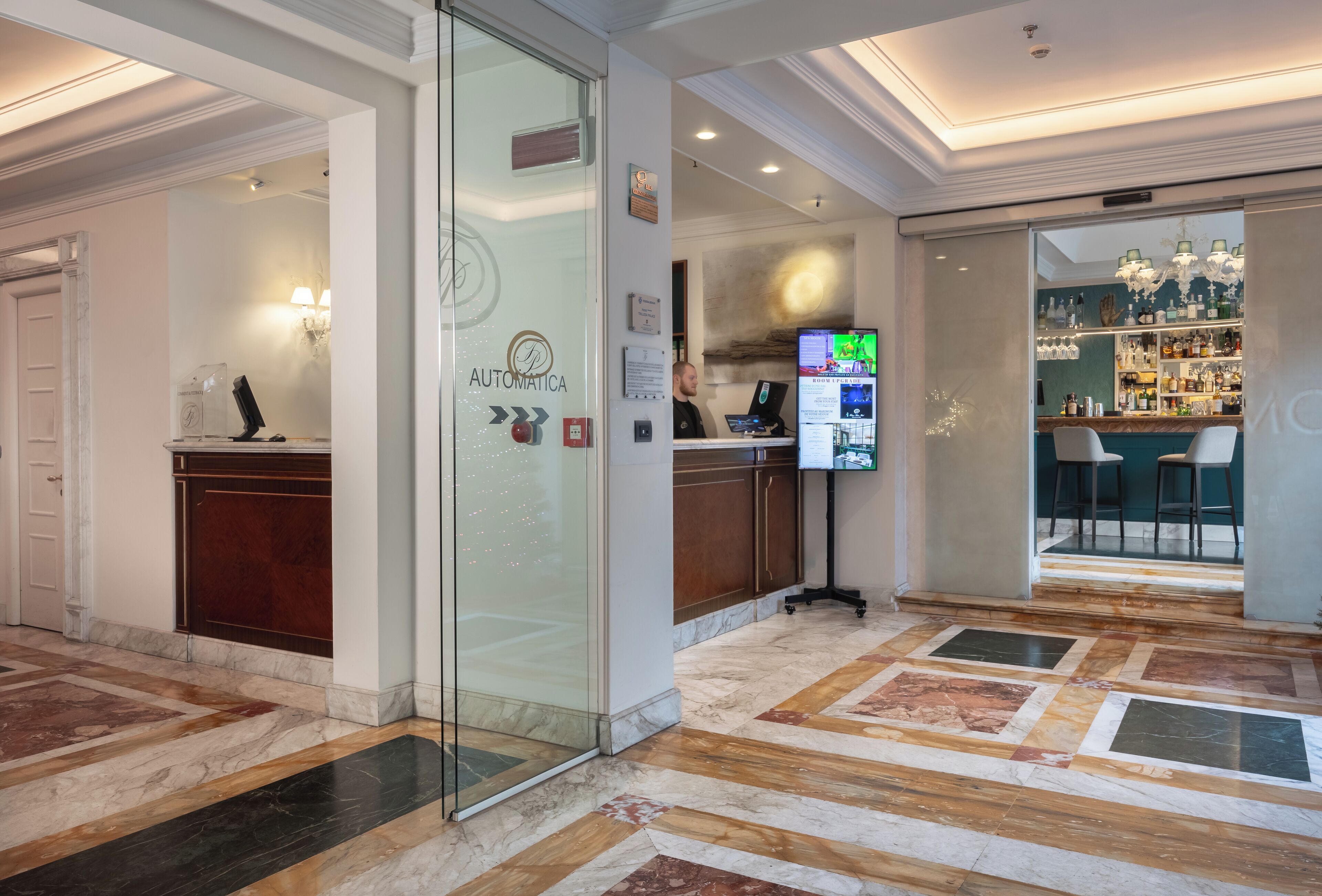 A hotel lobby with a reception desk, a bar area, and a marble floor.
