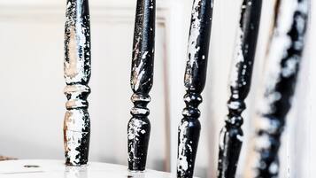 Primer plano de una silla con patas de madera pintadas en blanco y negro desgastadas y decorativas.