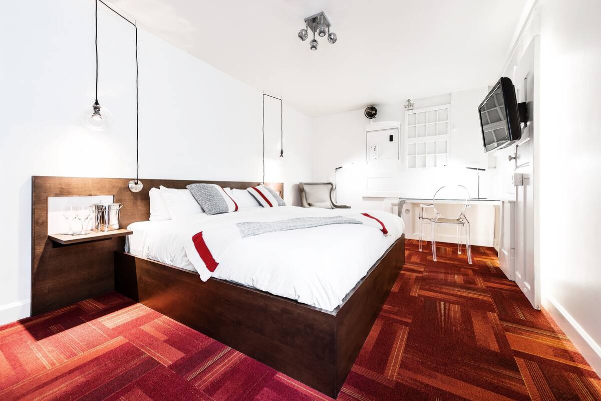 Une chambre moderne avec un lit en bois, des tables de chevet, un bureau et un téléviseur.