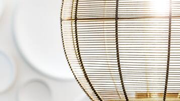 Een close-up van een lamp met een geweven, cilindrische kap.