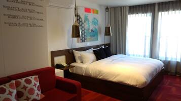 Una habitación de hotel con una cama grande, un sofá rojo y un aire acondicionado instalado en la pared.