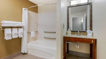 A bathroom with a bathtub, a shower, and a vanity with a mirror.
