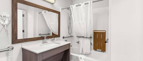 A modern bathroom with a large mirror, a sink, a shower, and a toilet.