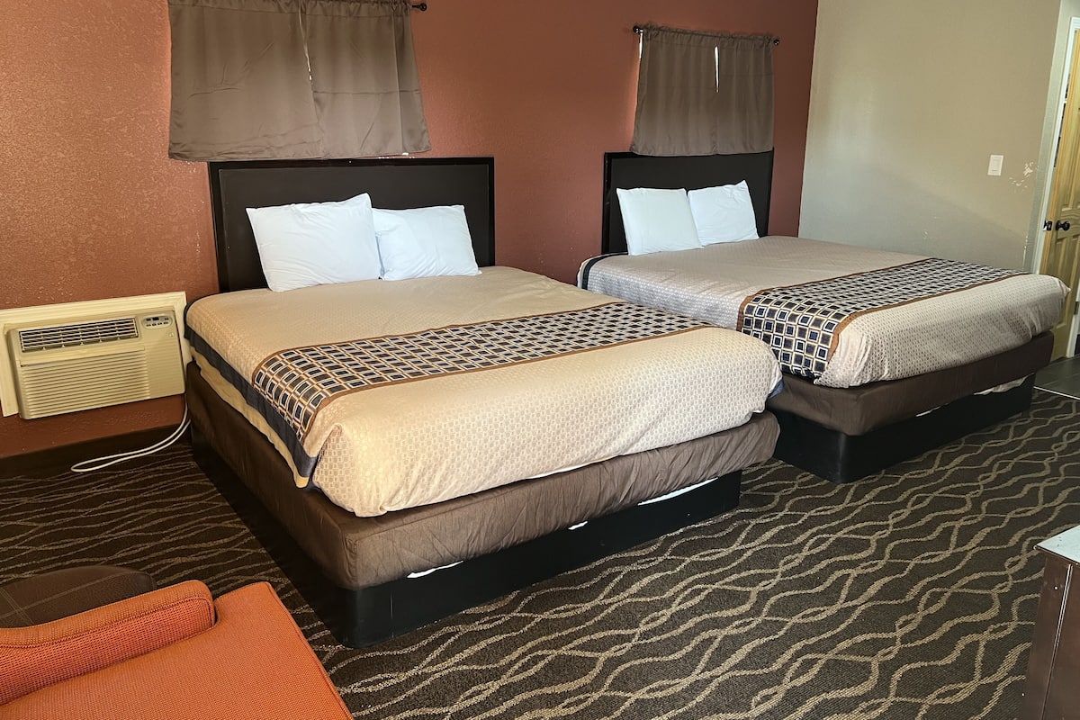 Habitación de hotel con dos camas, un calentador y una alfombra estampada.