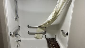 Bañera con cabezal de ducha, barras de apoyo y toallero.