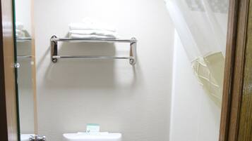 A bathroom with a white toilet, a glass shower enclosure, and a dark tiled floor.