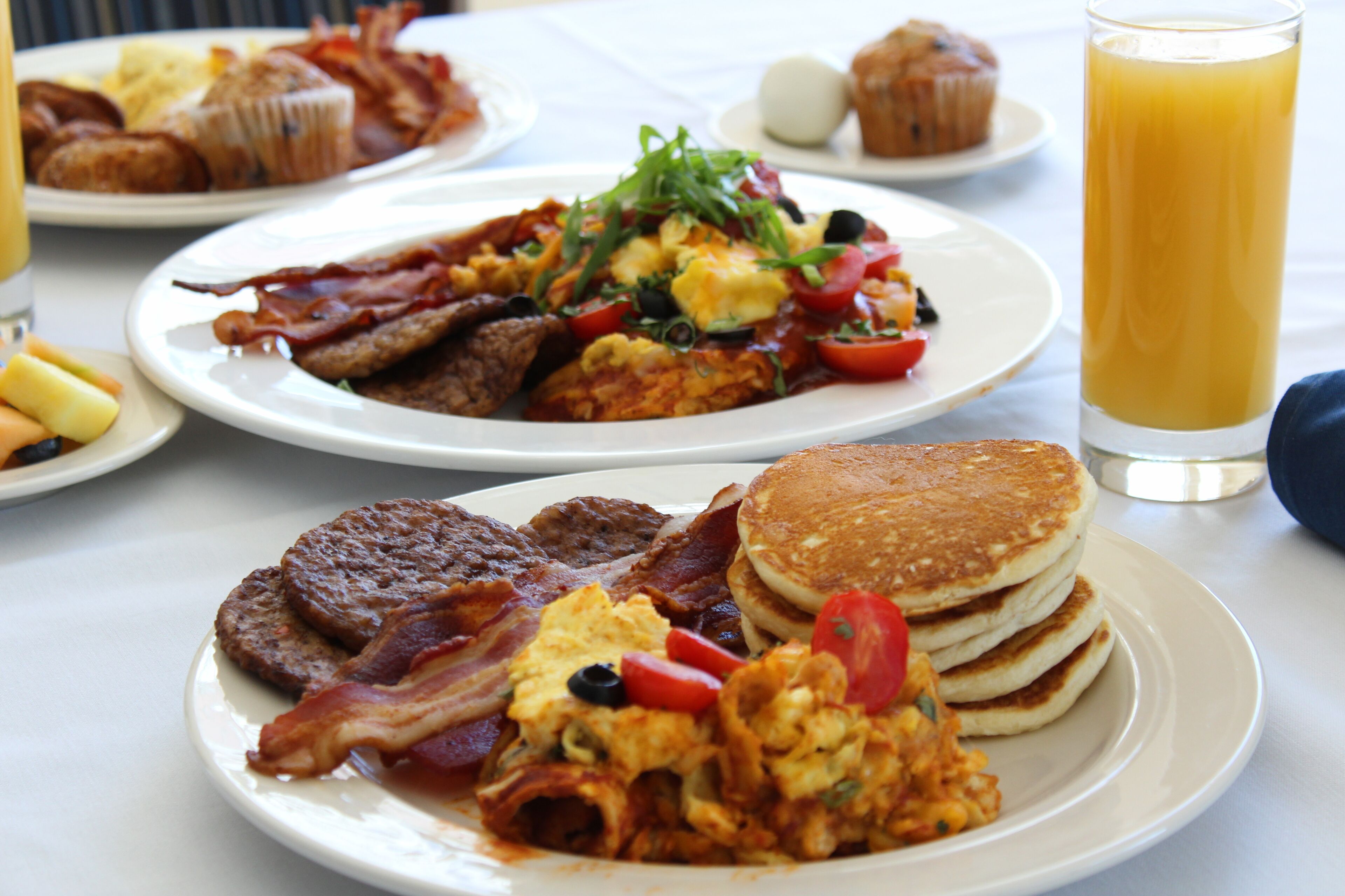 A breakfast spread with pancakes, bacon, eggs, and toast on a table.