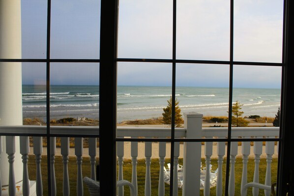 Vista do oceano através de uma janela com corrimão branco.