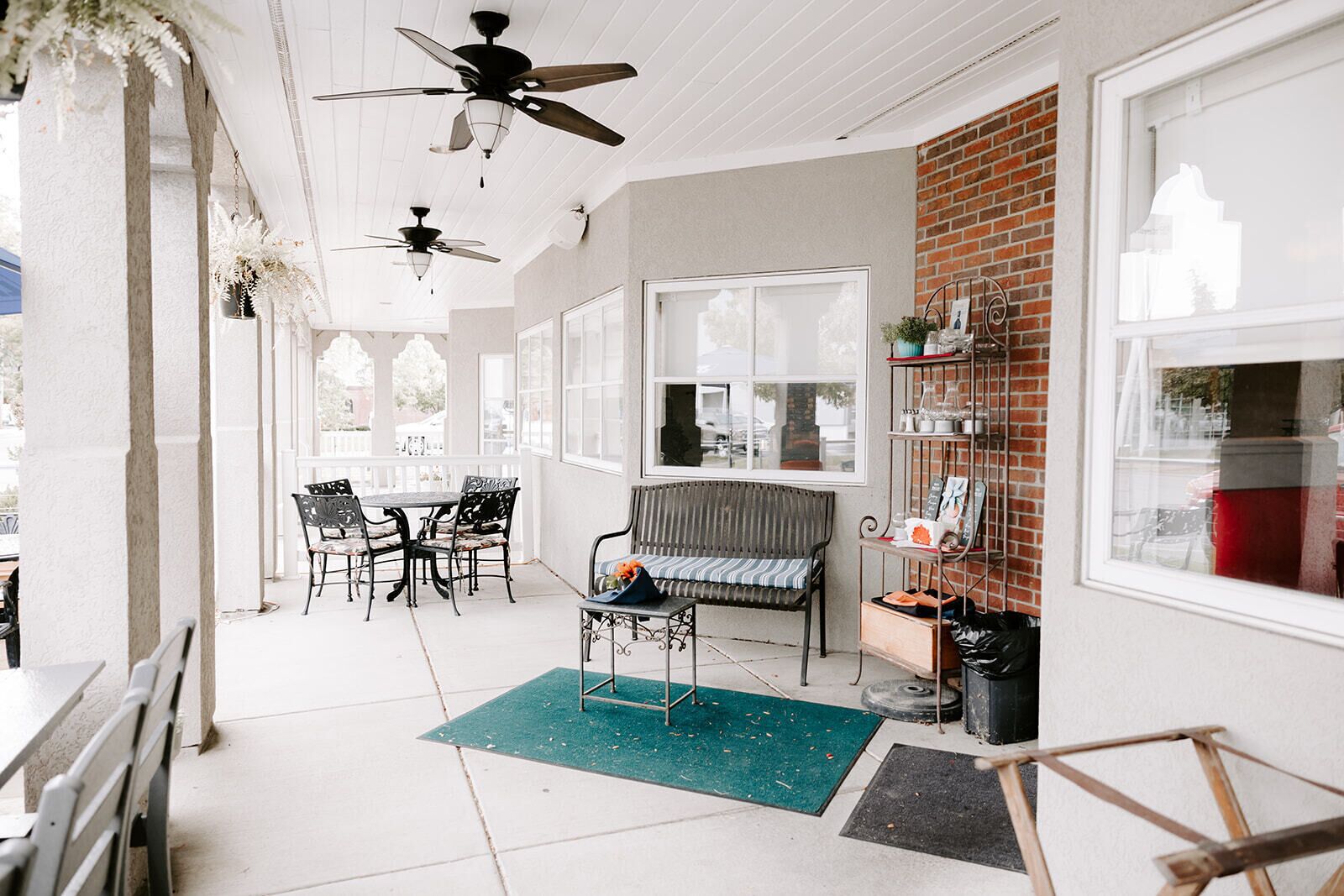A covered outdoor seating area with a table and chairs, a bench, and ceiling fans.