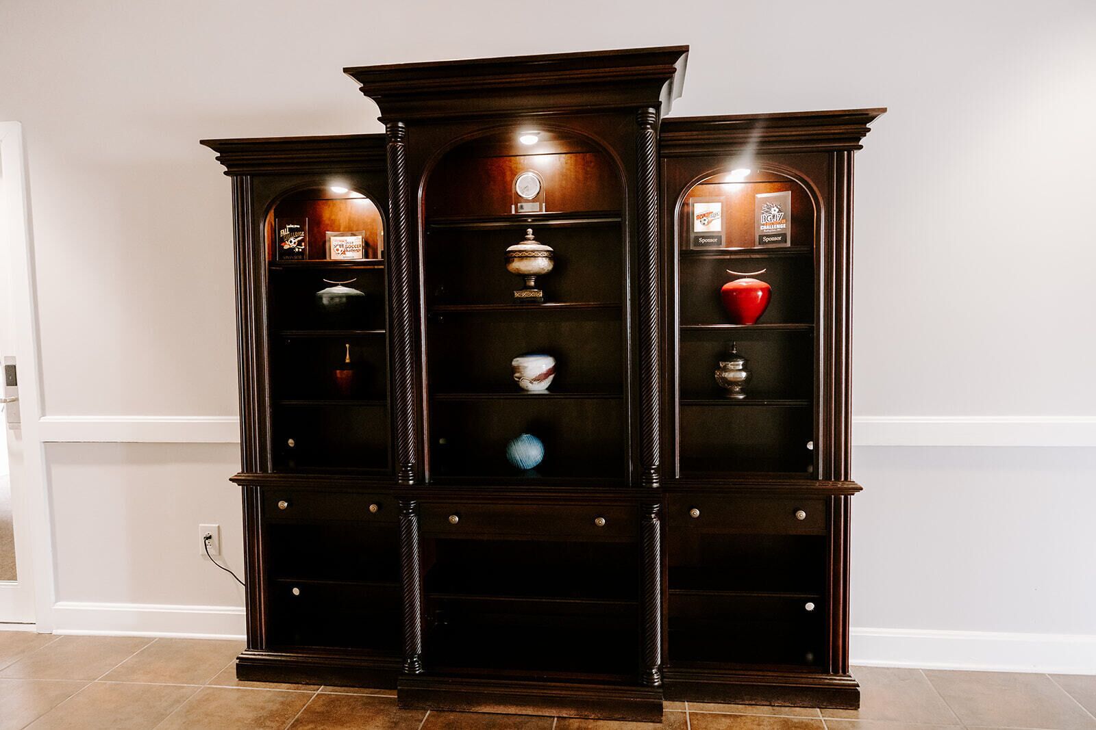 A dark wooden display cabinet with multiple shelves and glass doors, containing various decorative items.
