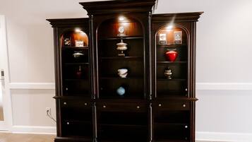 A dark wooden display cabinet with multiple shelves and glass doors, containing various decorative items.