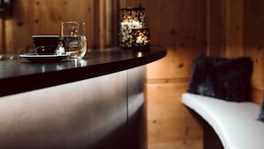 A wooden interior with a bar area featuring a cup, glass, and candle. - Hotel Lechnerhof (Unterfoehring)