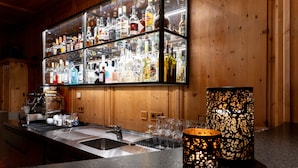 A bar area with a glass display case of liquor bottles, a coffee machine, and a decorative candle. - Hotel Lechnerhof (Unterfoehring)
