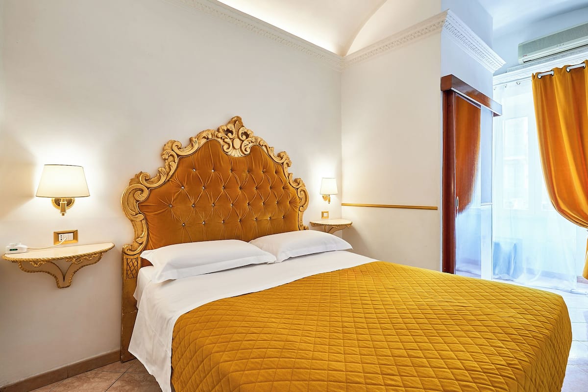 Une chambre d’hôtel avec un grand lit, deux tables de chevet avec des lampes et une fenêtre avec des rideaux.