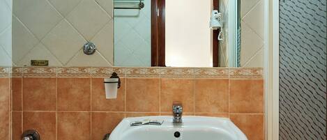 A bathroom with a sink, toilet, and mirror.