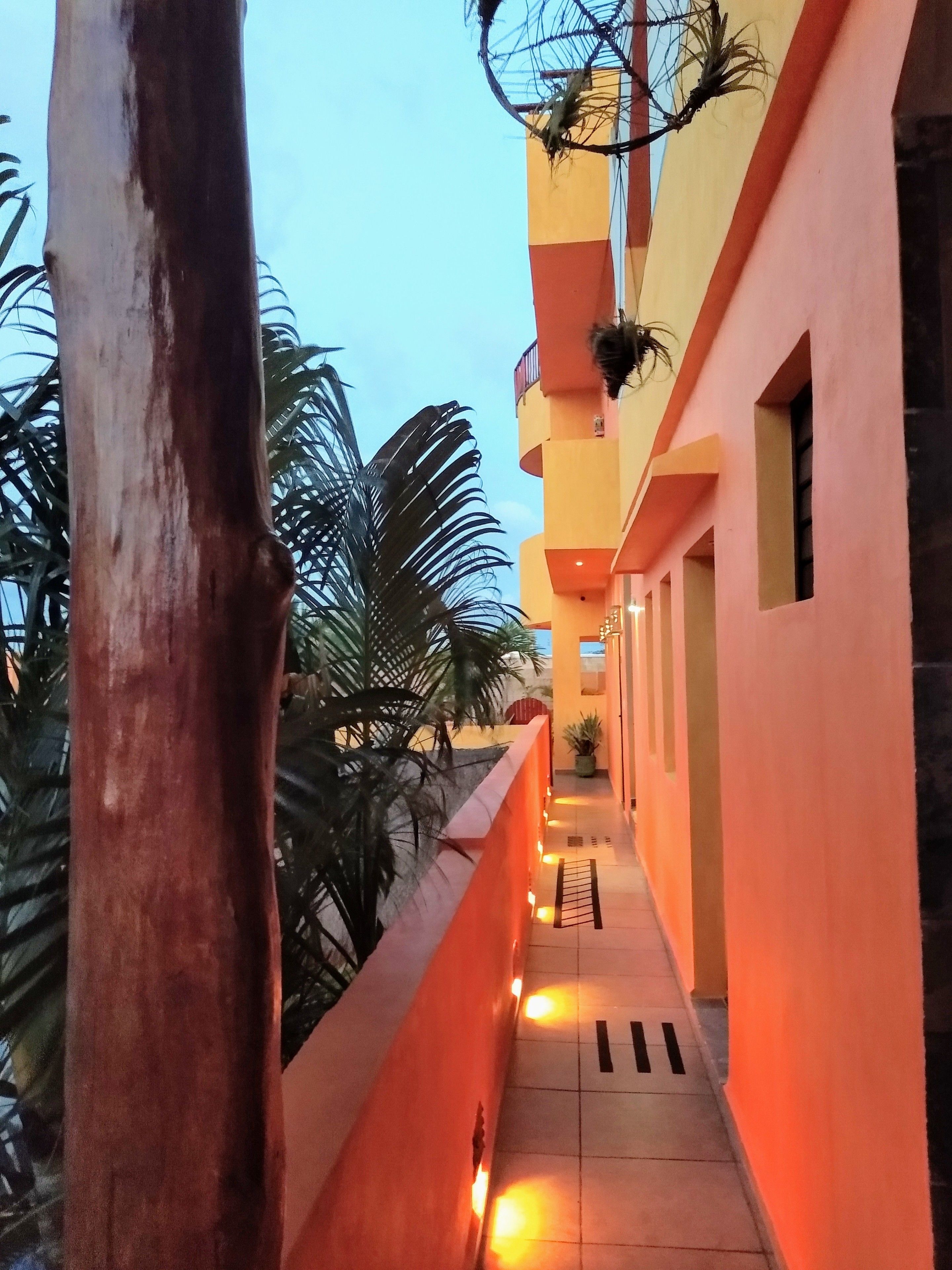 A corridor with a tiled floor, orange walls, and a railing on one side.