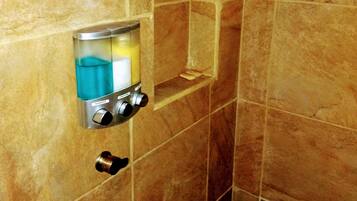 A bathroom with a shower area, a built-in shampoo dispenser, and a soap dish.
