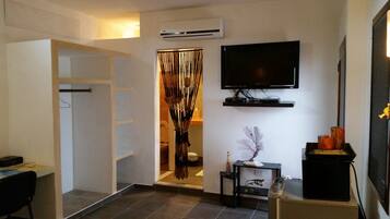 Una sala de estar moderna con un televisor de pantalla plana montado en la pared, un mueble negro para entretenimiento y una planta decorativa sobre una mesita.