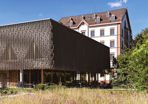 En moderne bygning med en facade af lægter og en ældre bygning i baggrunden.