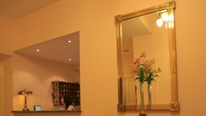 A reception area with a fireplace, a mirror, and a vase with flowers. - Anna Hotel (Prague)