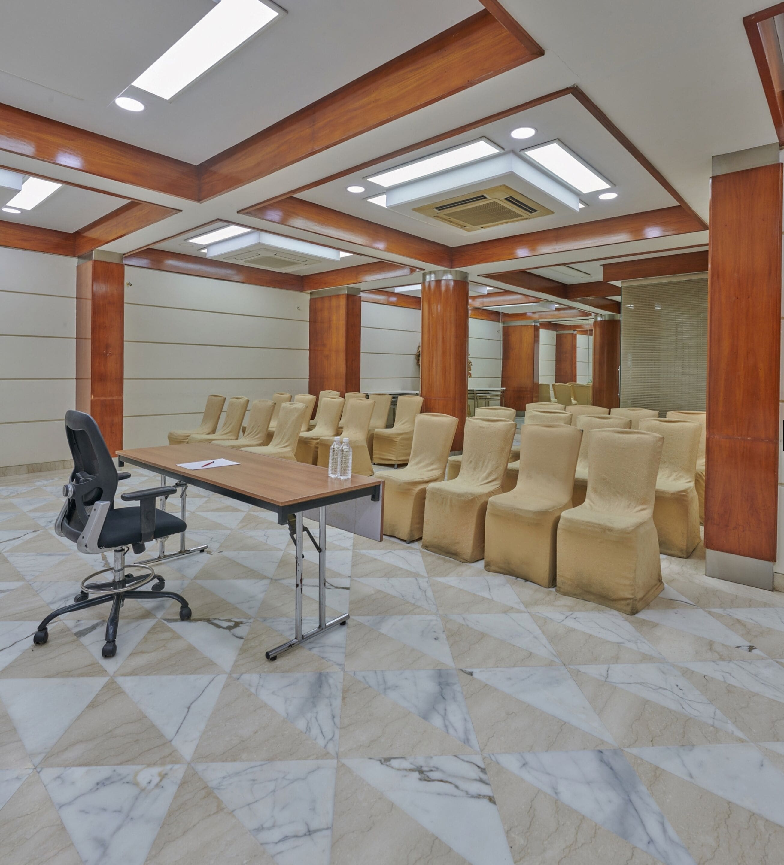 Un salón de conferencias con una larga mesa, varias sillas y un techo alto con tragaluces.