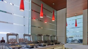A buffet area with multiple food stations, a wooden ceiling, and red pendant lights.