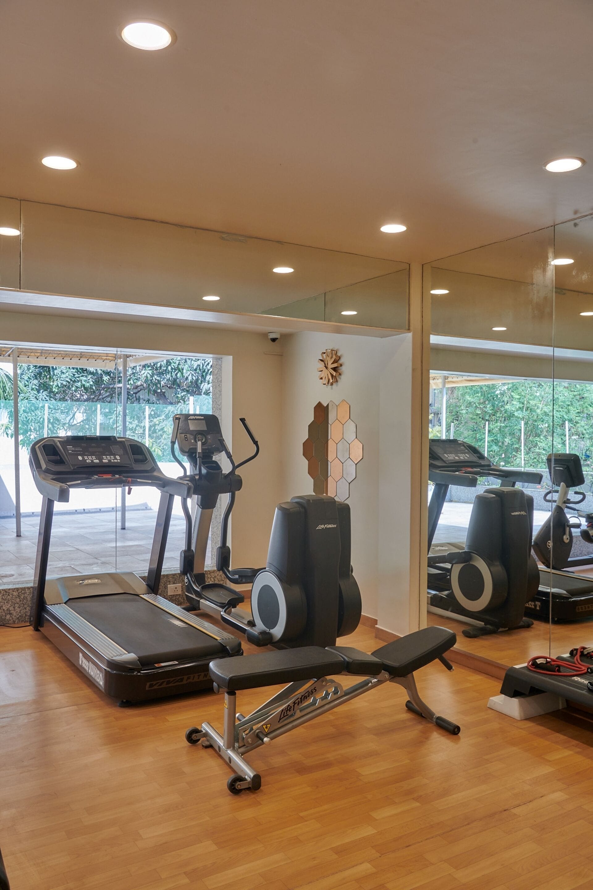 Un gimnasio con cintas de correr, una banca y una barra de pesas.
