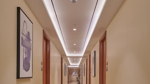A long, well-lit hallway with marble flooring and framed artwork on the walls.