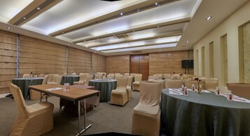A conference room with multiple tables and chairs, equipped with water bottles and notepads.
