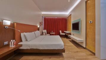 Ein modernes Hotelzimmer mit einem großen Bett, einem Schreibtisch, einem Fernseher und einem roten Vorhang.