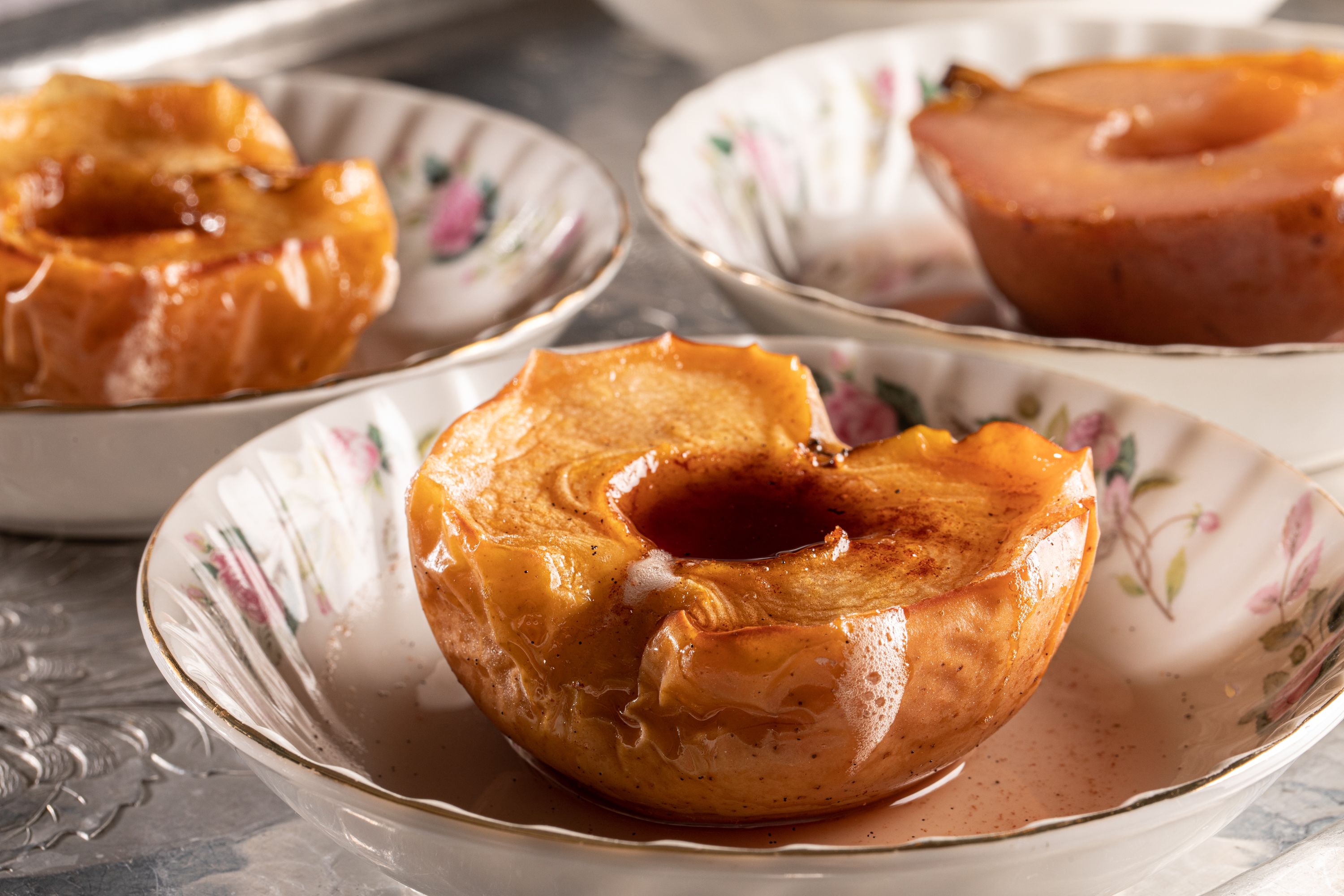 Three caramel apples on decorative plates.