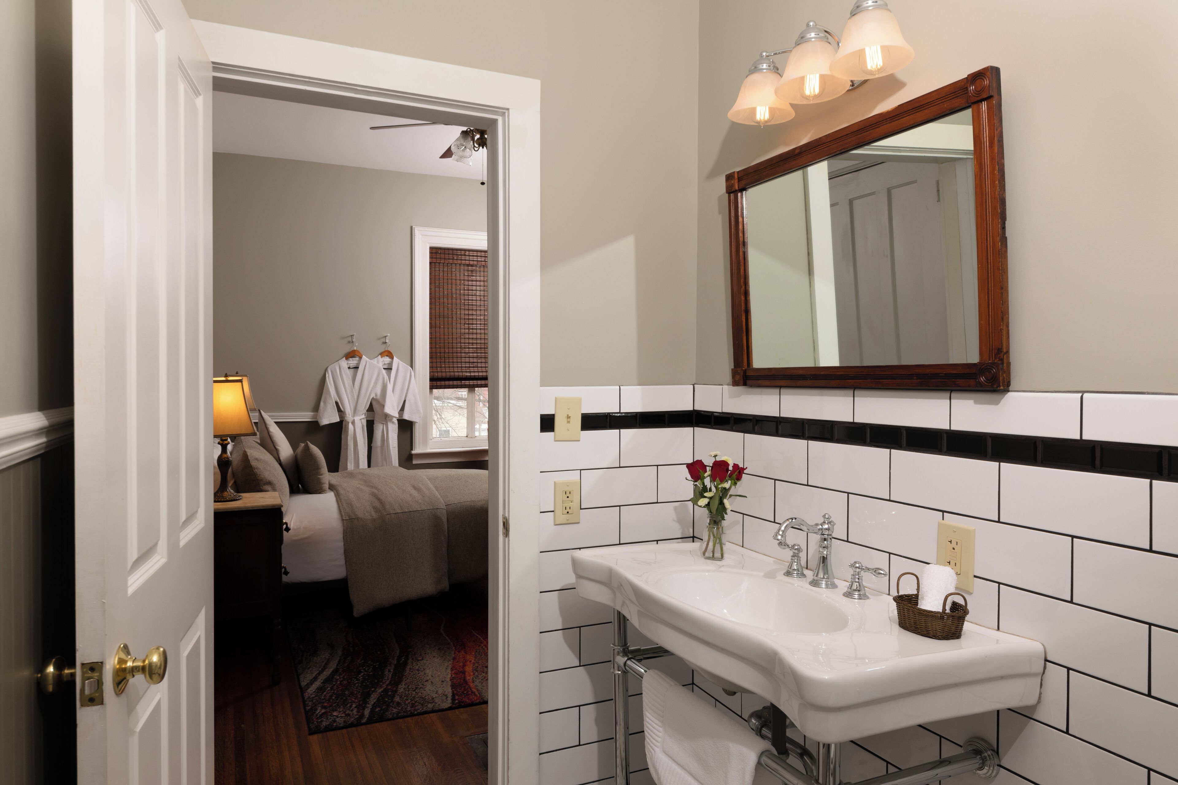 Un baño de hotel con un lavabo blanco, espejo y paredes con azulejos blanco y negro.