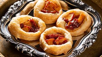 Four fruit tarts on an ornate silver tray.