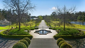 A symmetrical garden pathway leading to a central fountain, flanked by neatly trimmed hedges and trees. - The Convent Hunter Valley Hotel (Pokolbin)