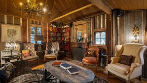 A cozy, wood-paneled room with a fireplace, leather armchairs, a bookshelf, and a chandelier. - The Convent Hunter Valley Hotel (Pokolbin)