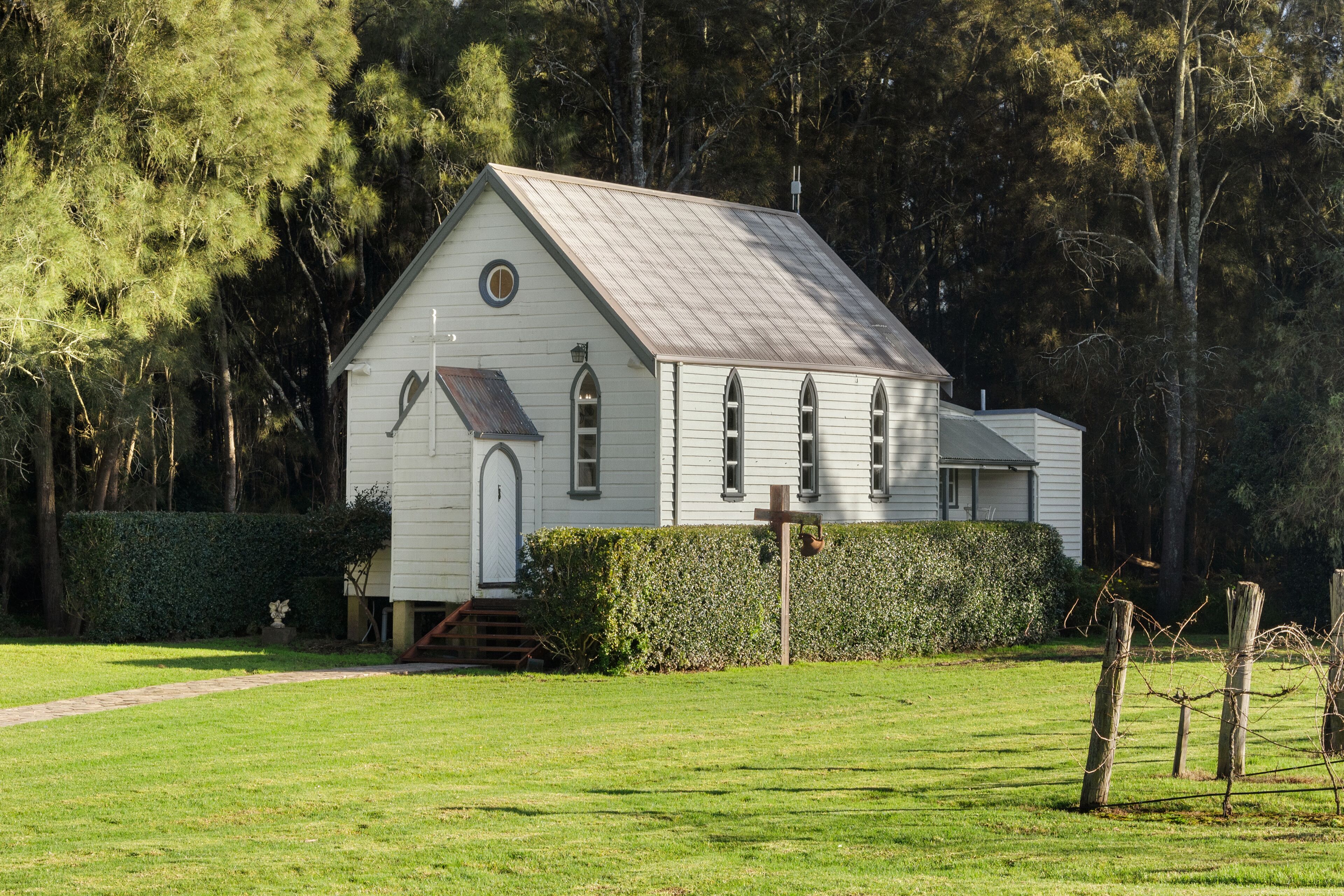 A white church with a gabled roof, a small porch, and a cross in front.