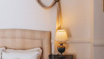 Una cama bien hecha con almohadas, una lámpara de noche y una mesita de madera con un cajón.