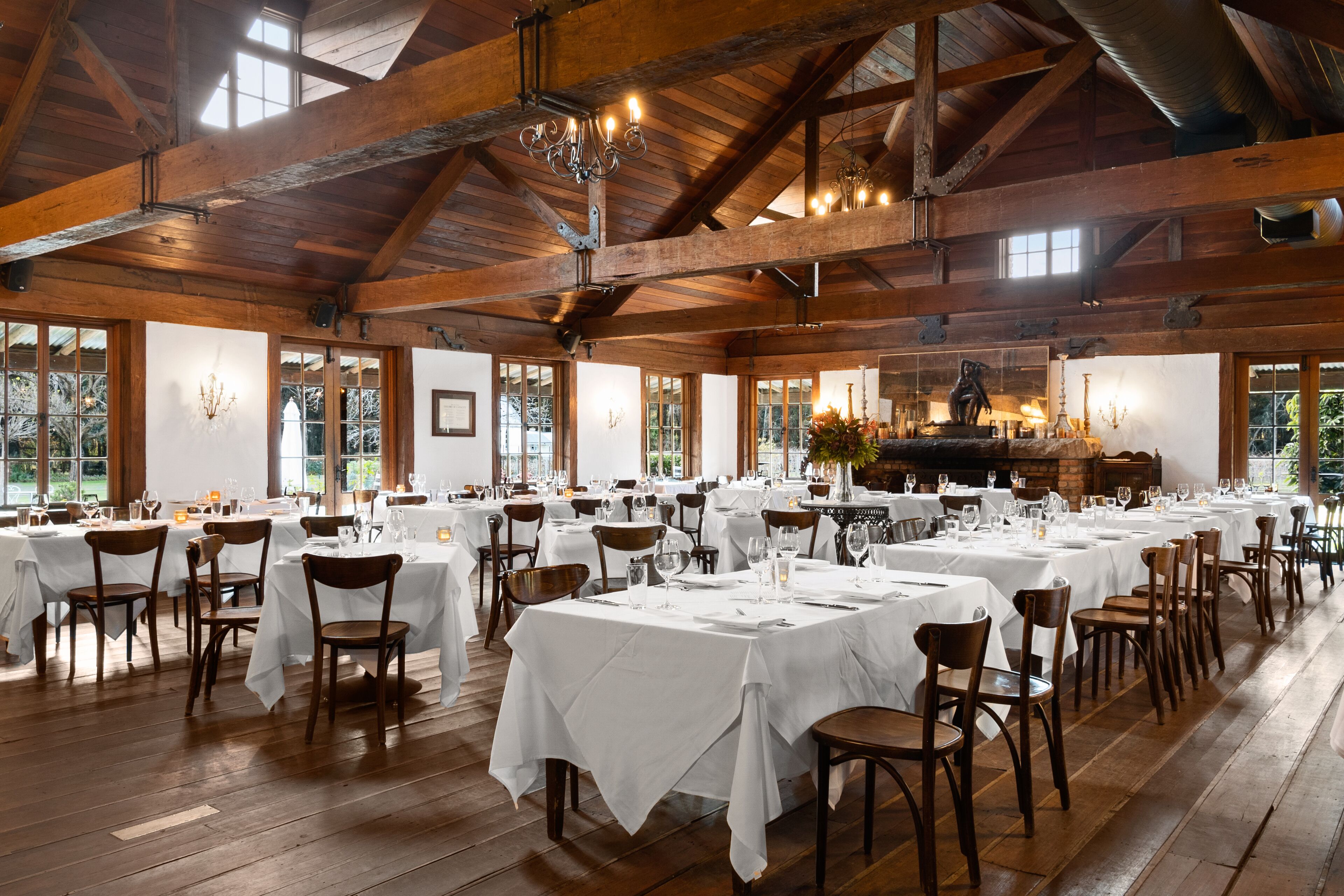 Une vaste salle à manger avec de hauts plafonds en bois et de nombreuses tables dressées pour un événement officiel.