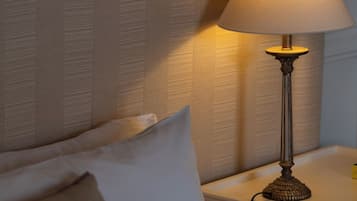Una cama con cabecera, una lámpara de noche y un almohadón.