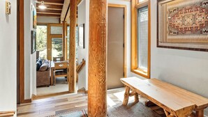 A wooden interior with a bench, a large wooden column, and a patterned wall. - Evergreen Condominiums by Vail Resorts (Keystone)