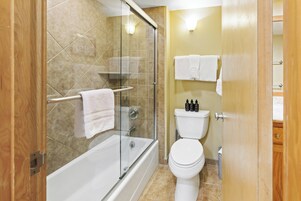 Une salle de bain avec une douche à parois de verre, une baignoire, des toilettes et une porte en bois.