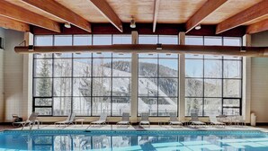 A swimming pool with lounge chairs and large windows with a mountain view. - Evergreen Condominiums by Vail Resorts (Keystone)
