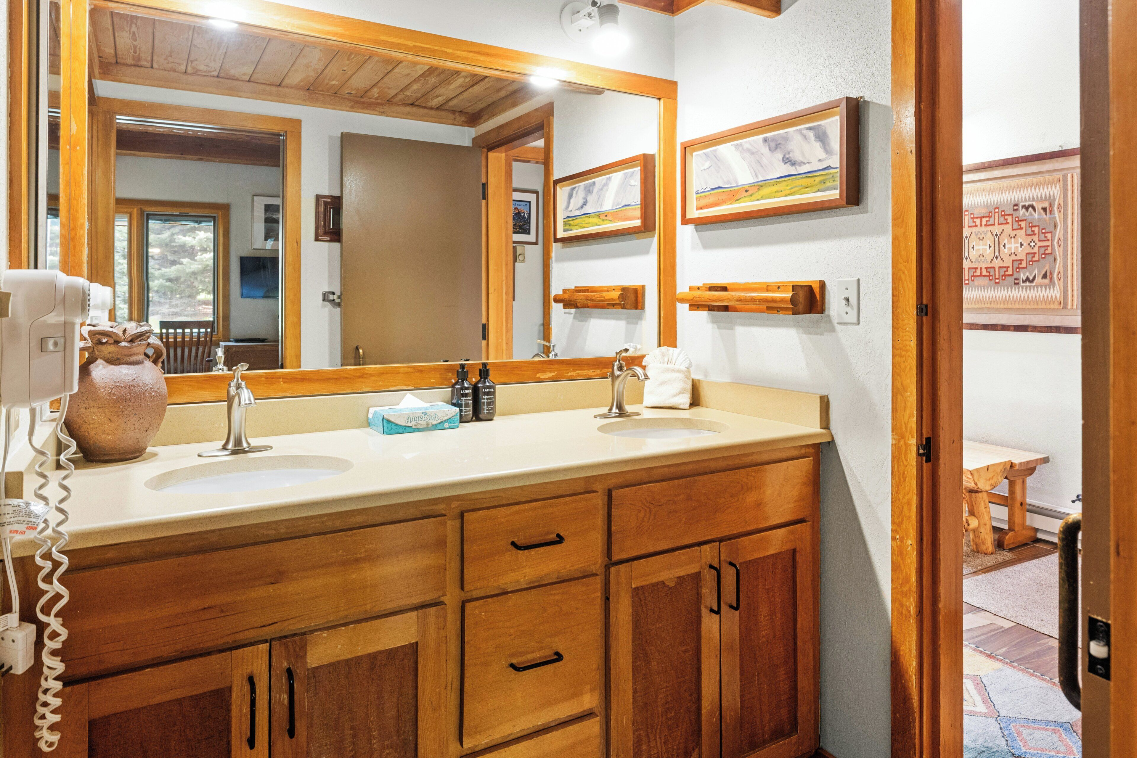 A bathroom with wooden cabinets, a double sink, and a large mirror.