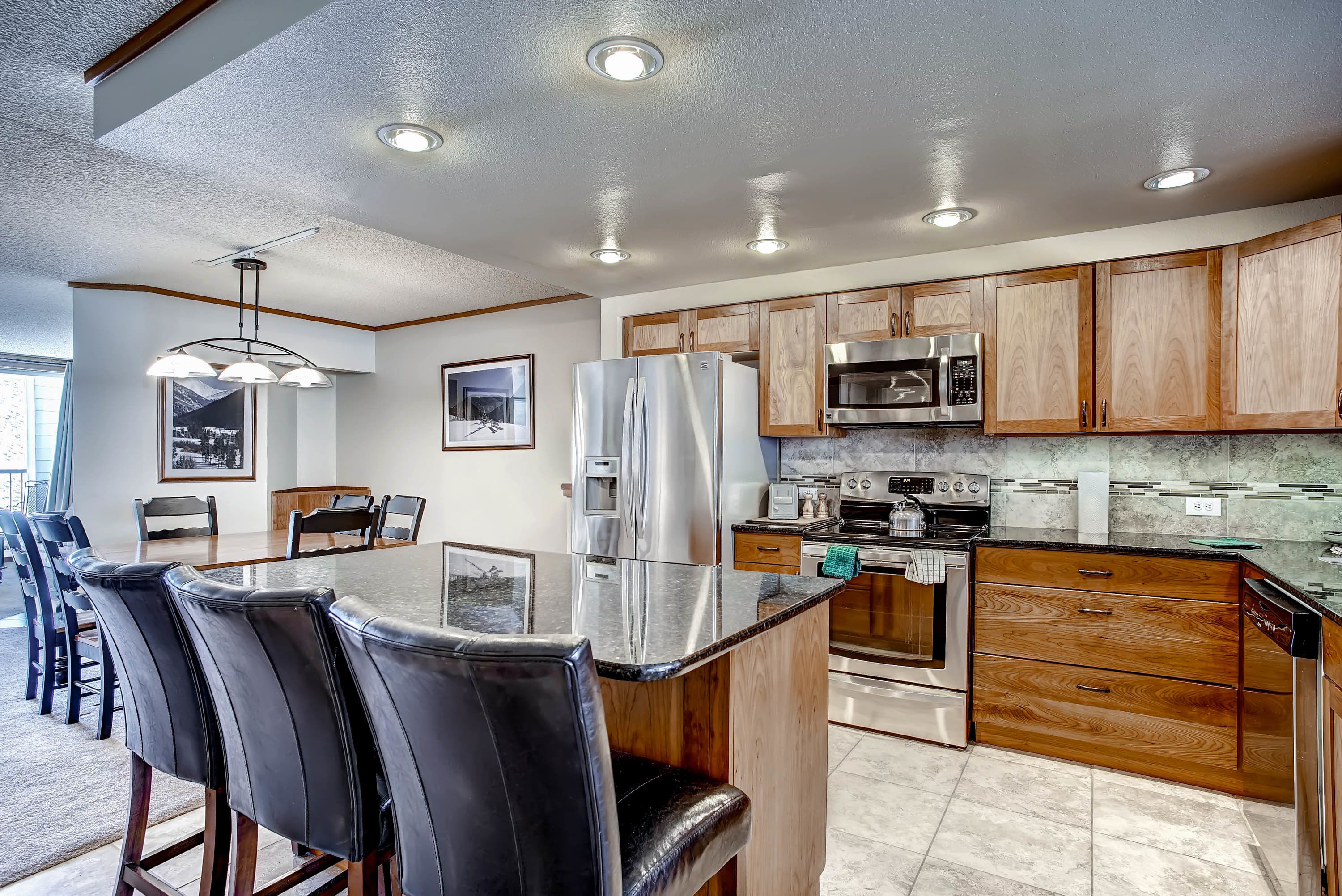A modern kitchen with wooden cabinets, stainless steel appliances, and a central island with seating.