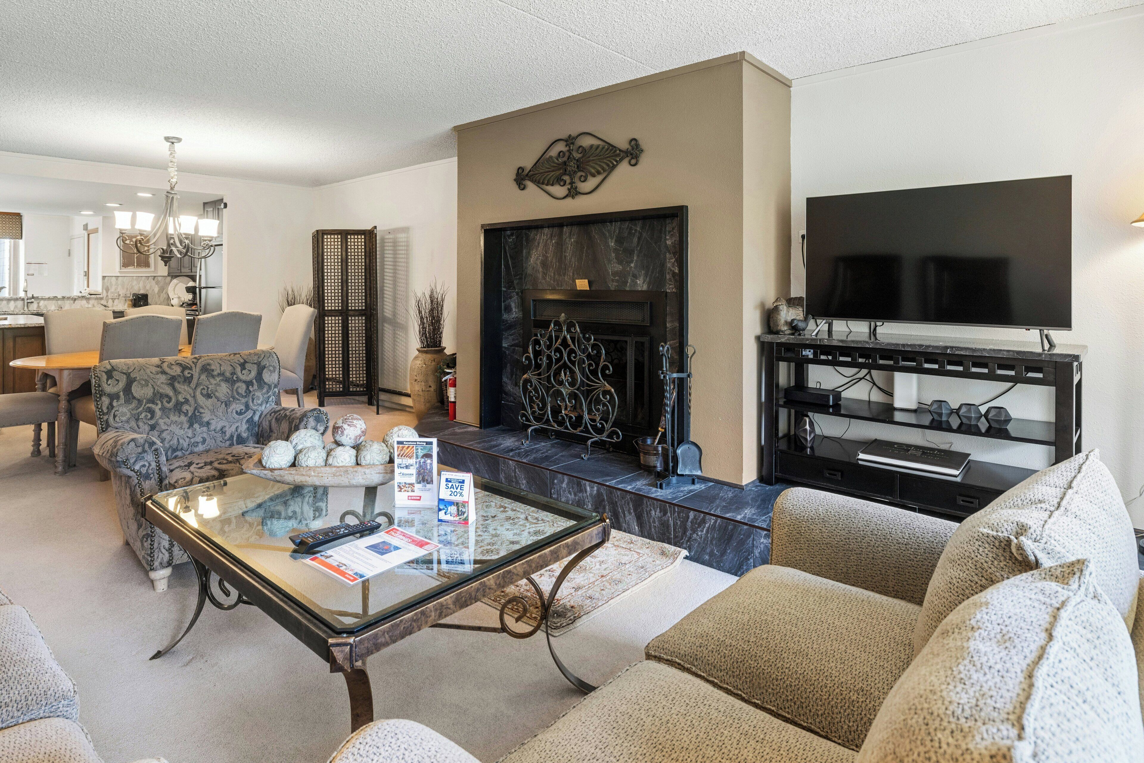 A living room with a fireplace, a television, and a dining area with chairs and a table.