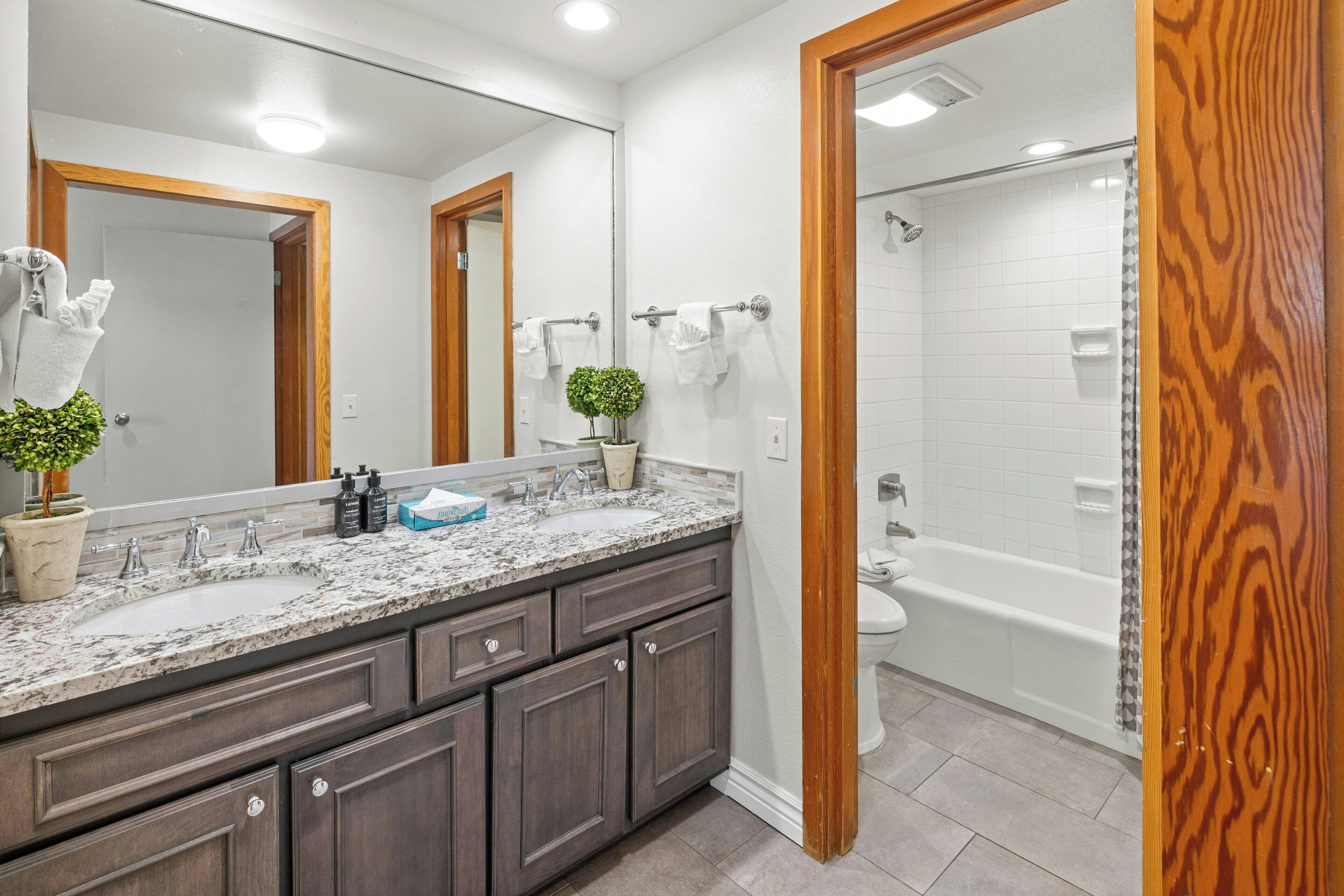 Une salle de bain avec un grand miroir, un lavabo, des toilettes et une douche.