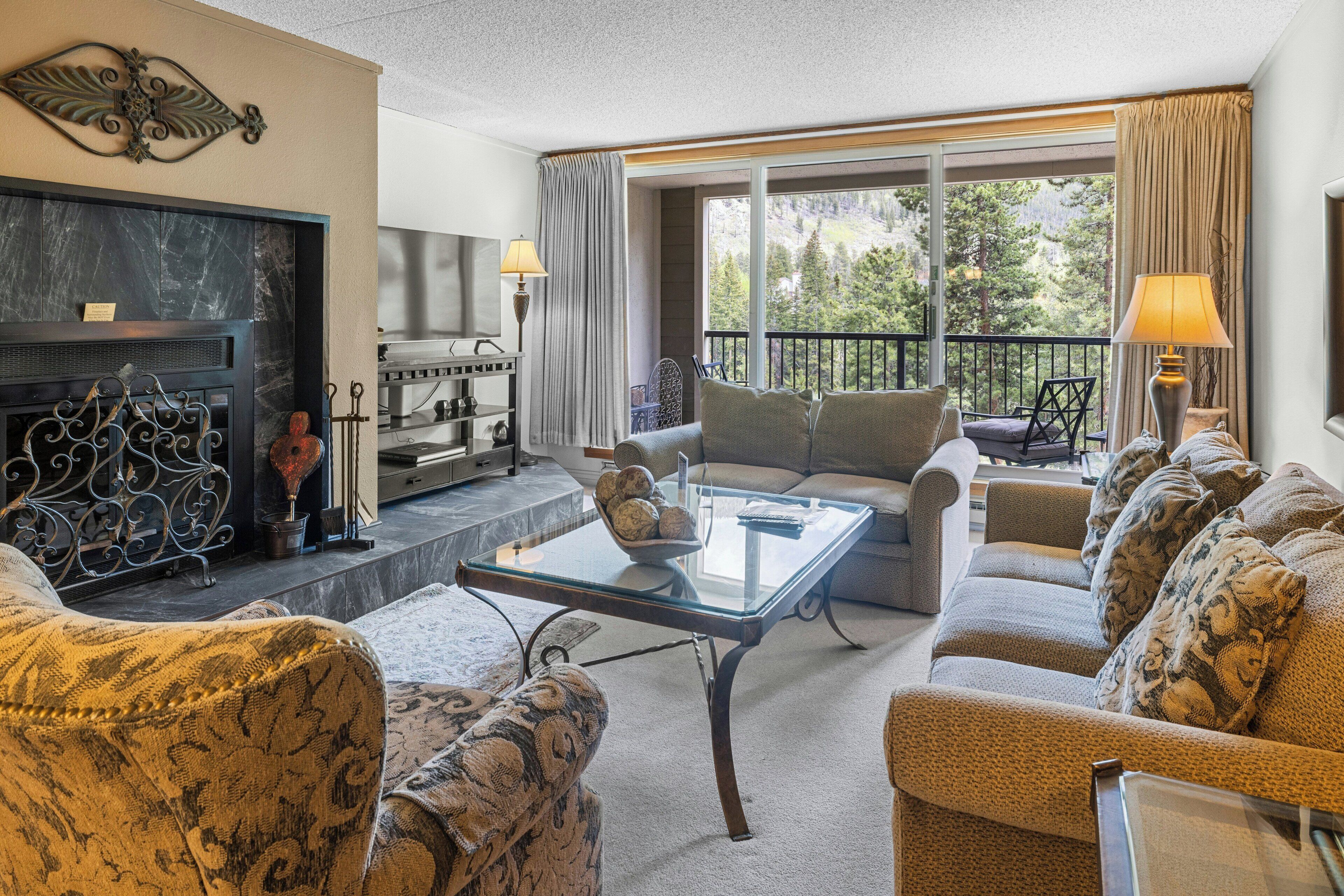 A living room with a fireplace, a glass coffee table, and a sofa set.