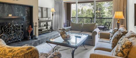 A living room with a fireplace, a glass coffee table, and a sofa set.