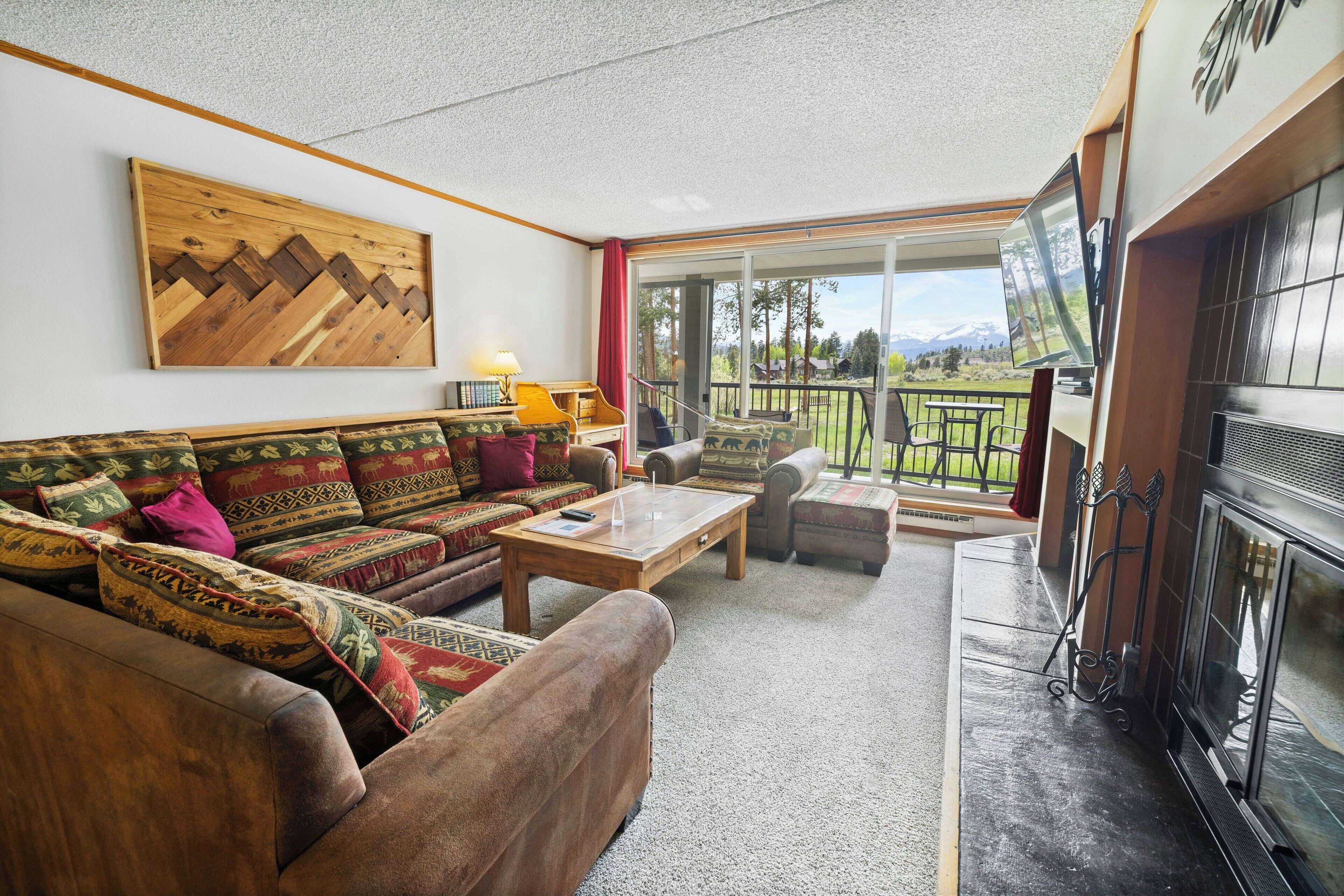 A living room with a sofa, armchairs, a coffee table, a fireplace, and a television.
