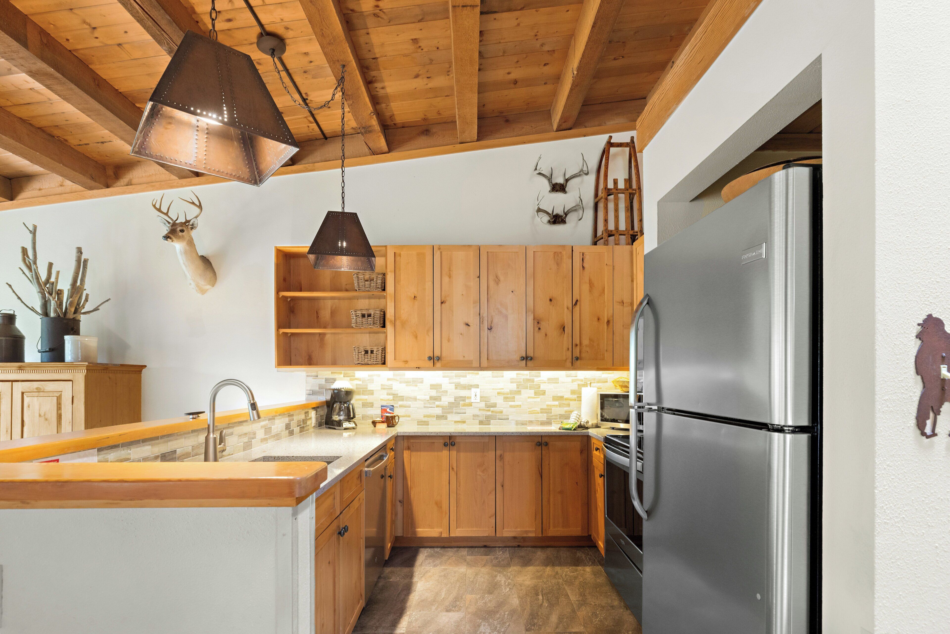 Eine Küche mit Holzschränken, einem Edelstahl-Kühlschrank, einer Pendelleuchte und montierten Hirschgeweihen.